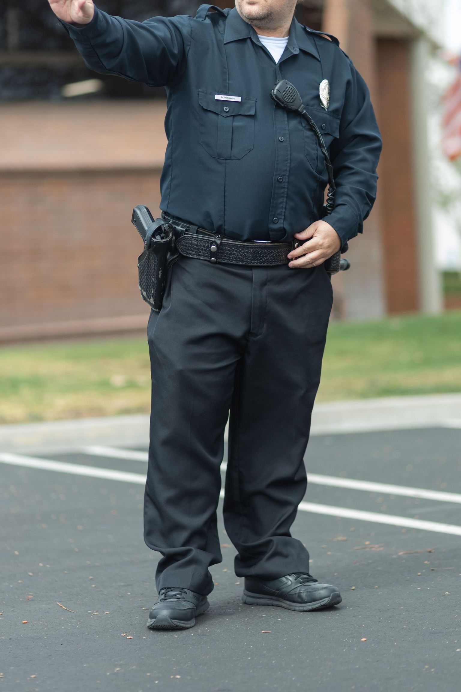 A caucasian police officer in uniform directing traffic outdoors during the daytime.