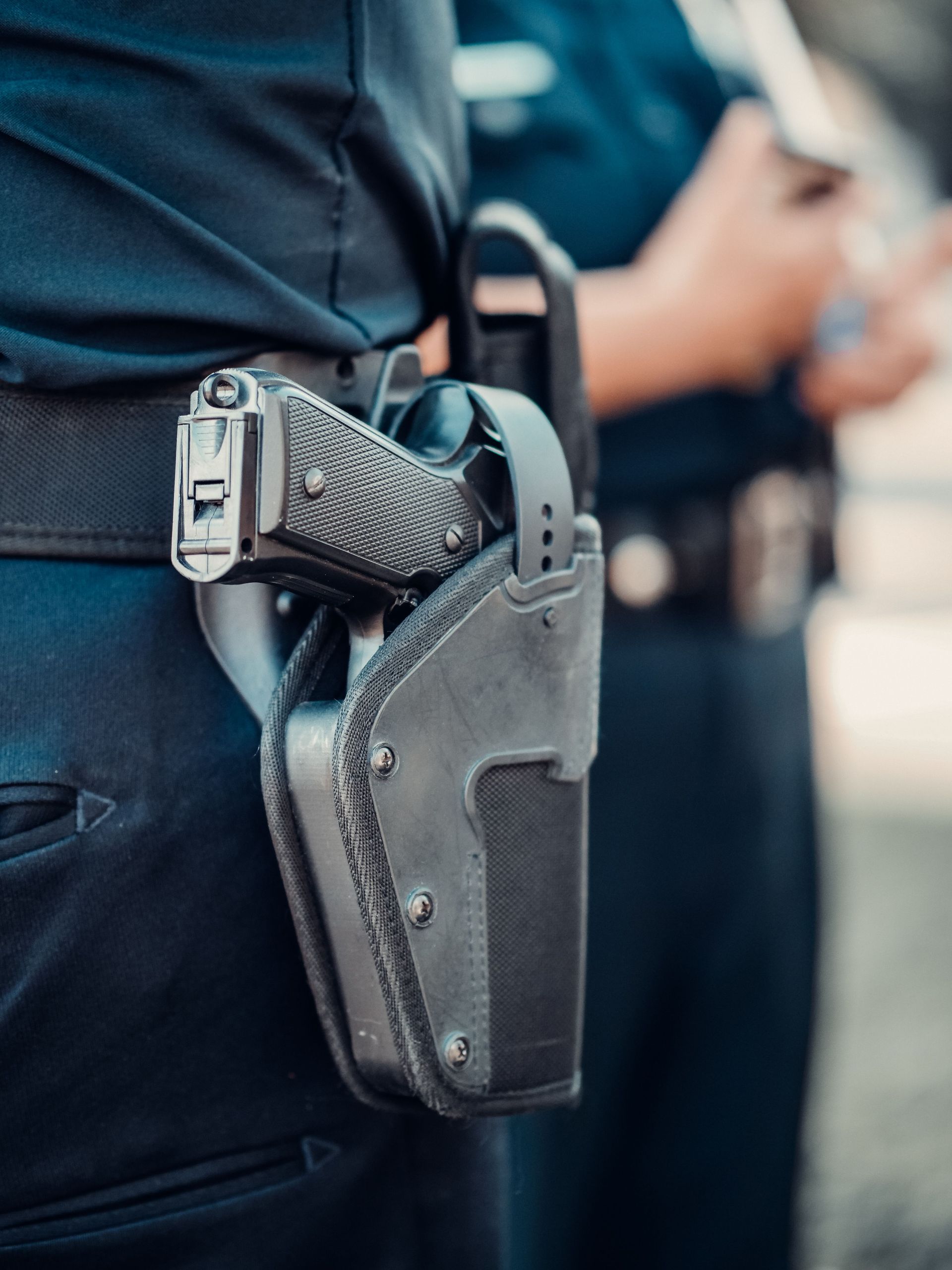 Detailed view of a police officer's gun holstered on the belt with blurred background.