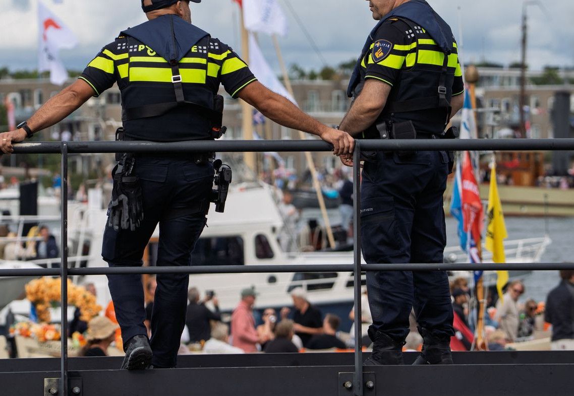 Two police officers watch over a bustling harbor event with boats and attendees.