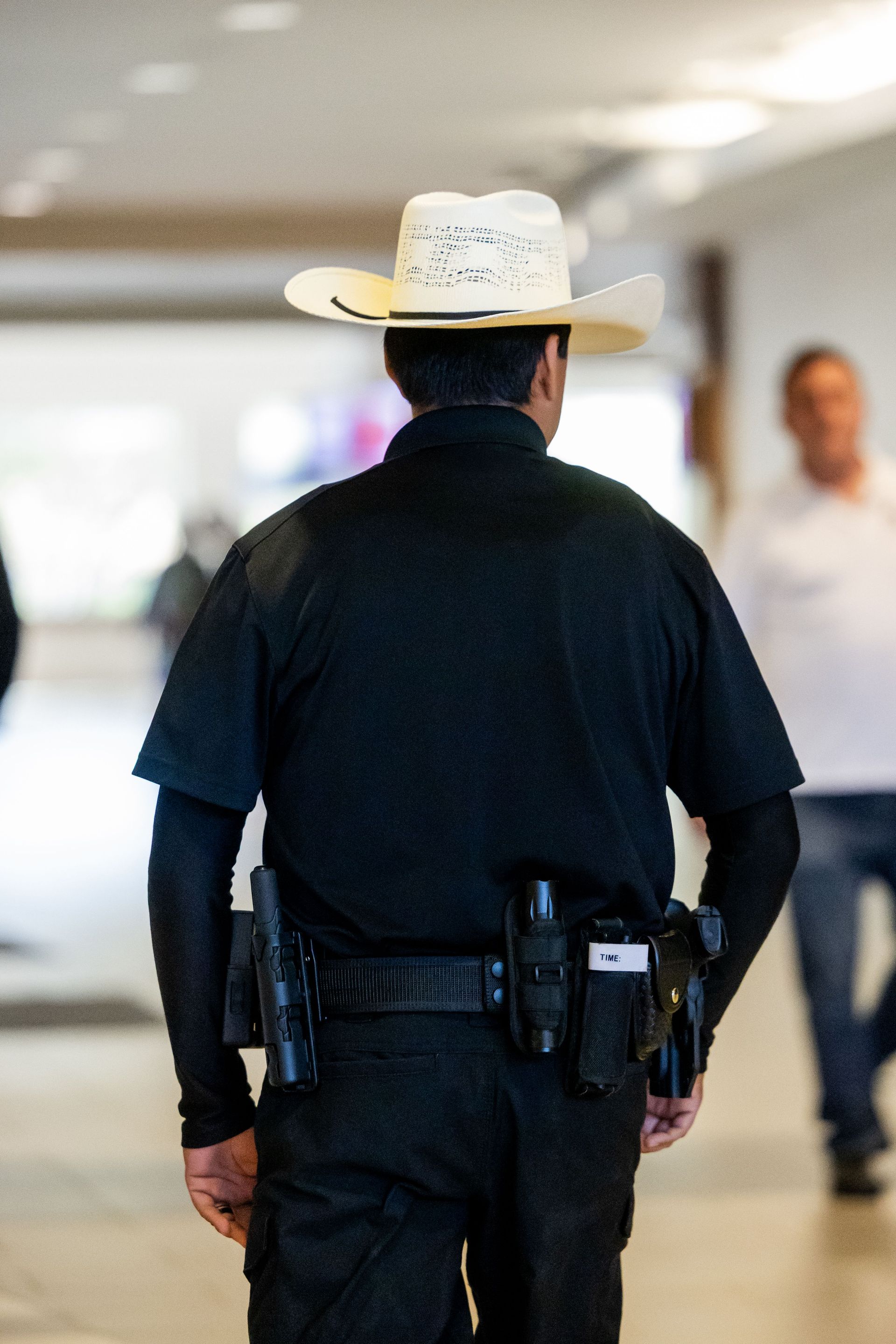 Security guard with cowboy hat patrolling inside a building, showcasing law enforcement and security themes.