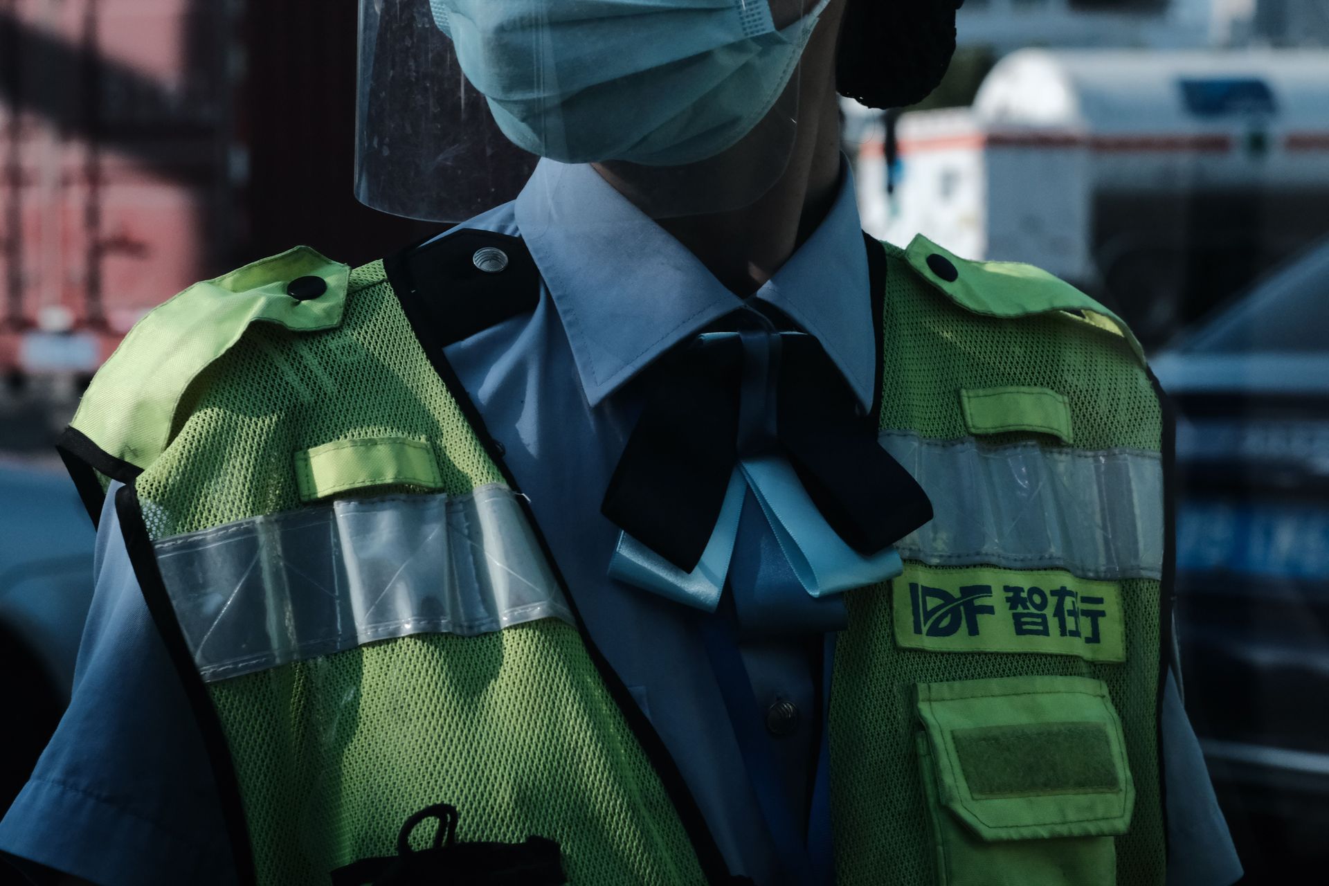 A close-up image of a police officer wearing a face mask and high-visibility vest.
