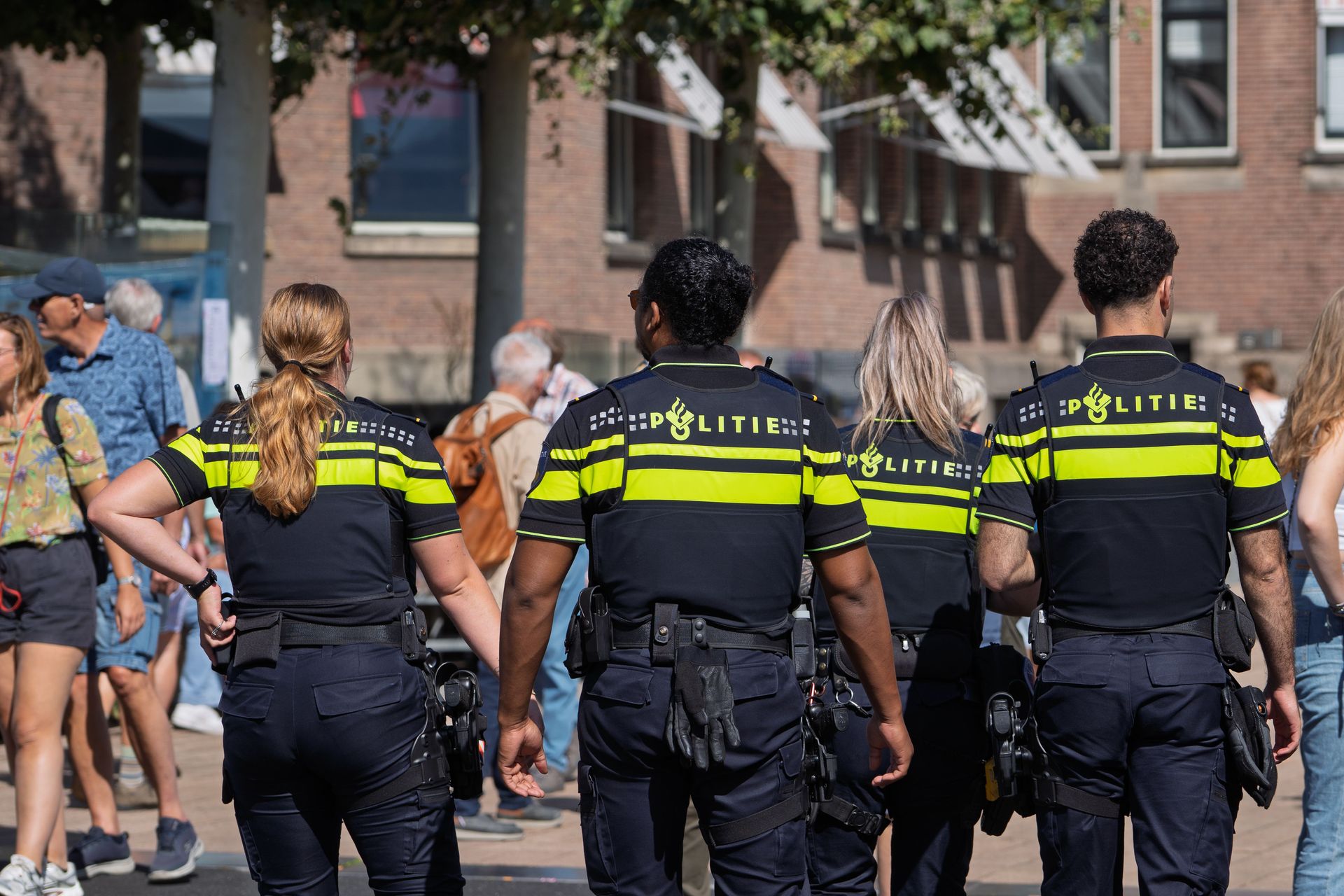 Dutch police officers patrolling a busy urban area during daytime, ensuring public safety.