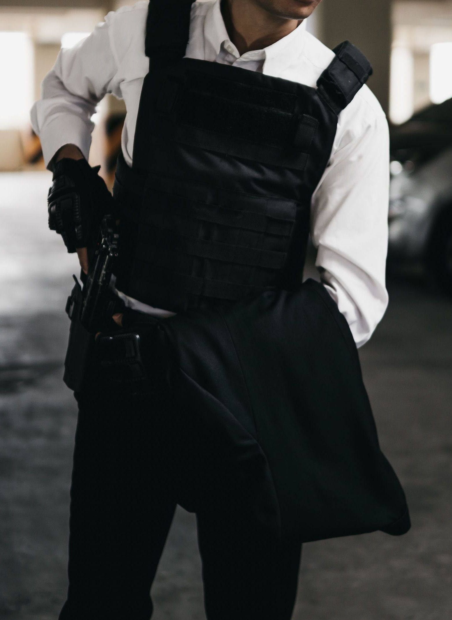Man in a bulletproof vest and sunglasses in an underground parking lot.
