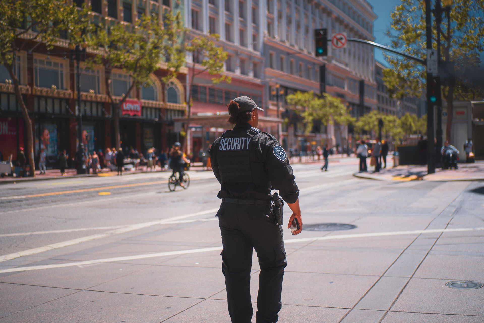 A security officer patrols a bustling street in San Francisco, capturing daily urban life.