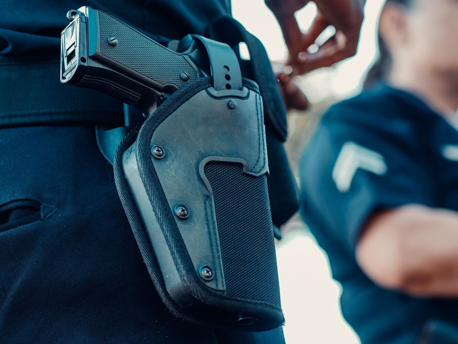 Police officers with a focus on a holstered handgun, demonstrating law enforcement readiness.