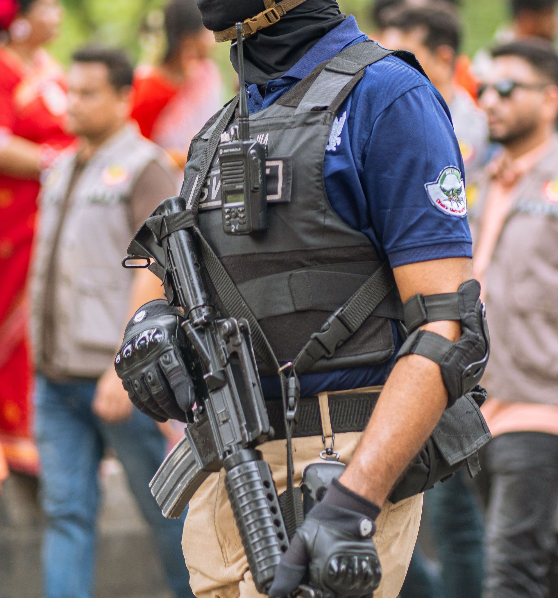 A tactical officer wearing protective gear equipped with communication devices at an outdoor event.